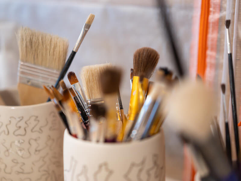 Various paintbrushes in a ceramic cup